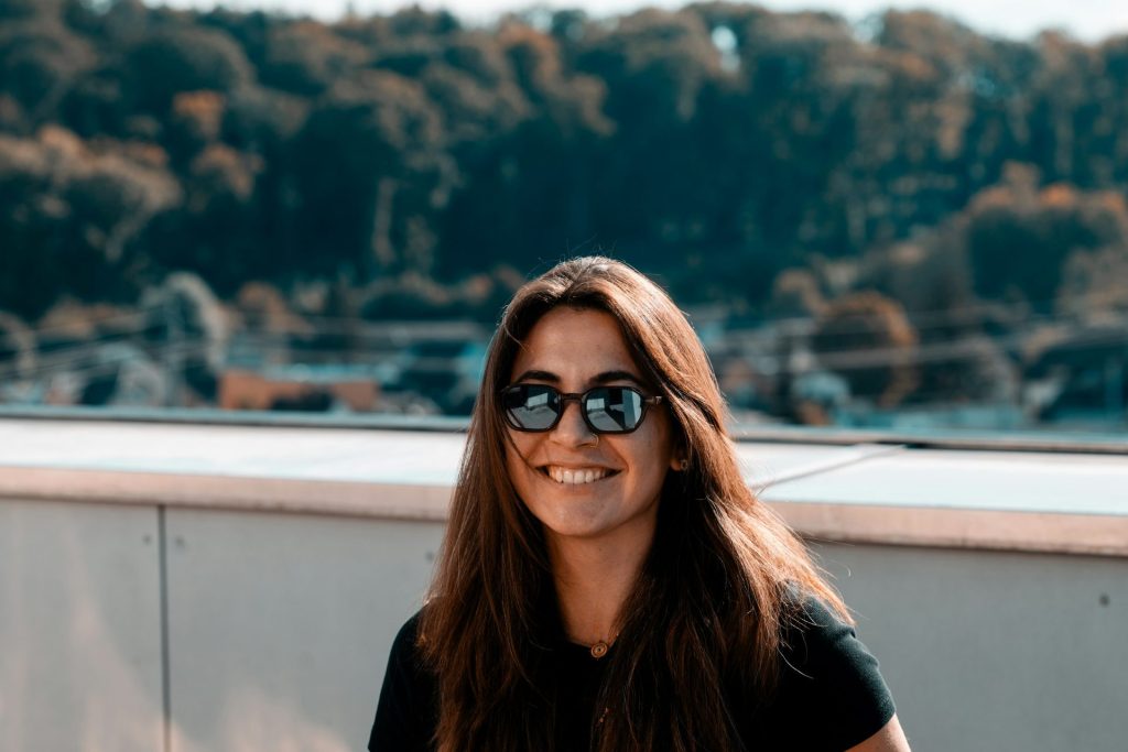 Eine Frau mit Sonnenbrille sitzt auf einem Sims.